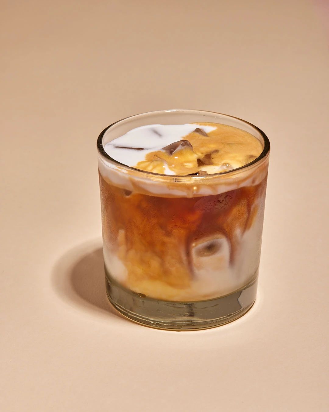 Iced oat latte, unstirred, in a rocks glass
